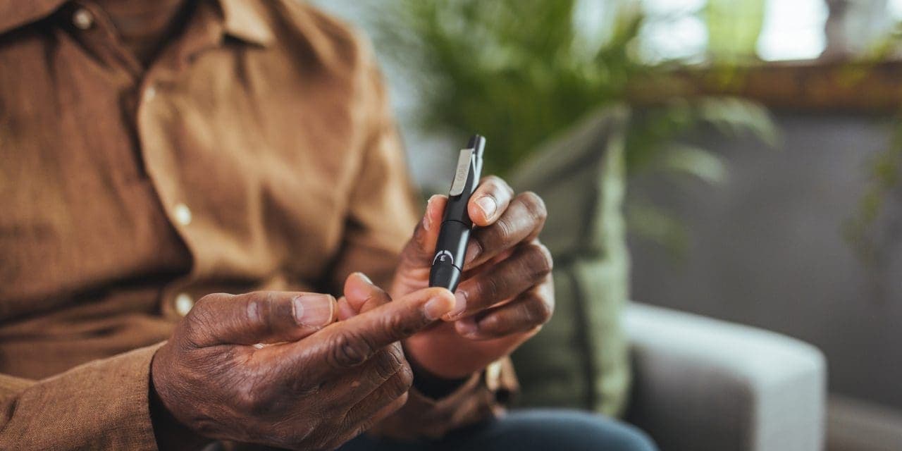 man sitting and taking blood from his finger due to diabetes.